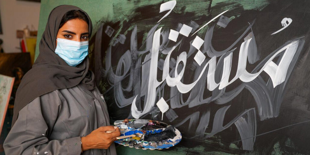 Une artiste qui a écrit le futur en arabe en blanc avec de la peinture